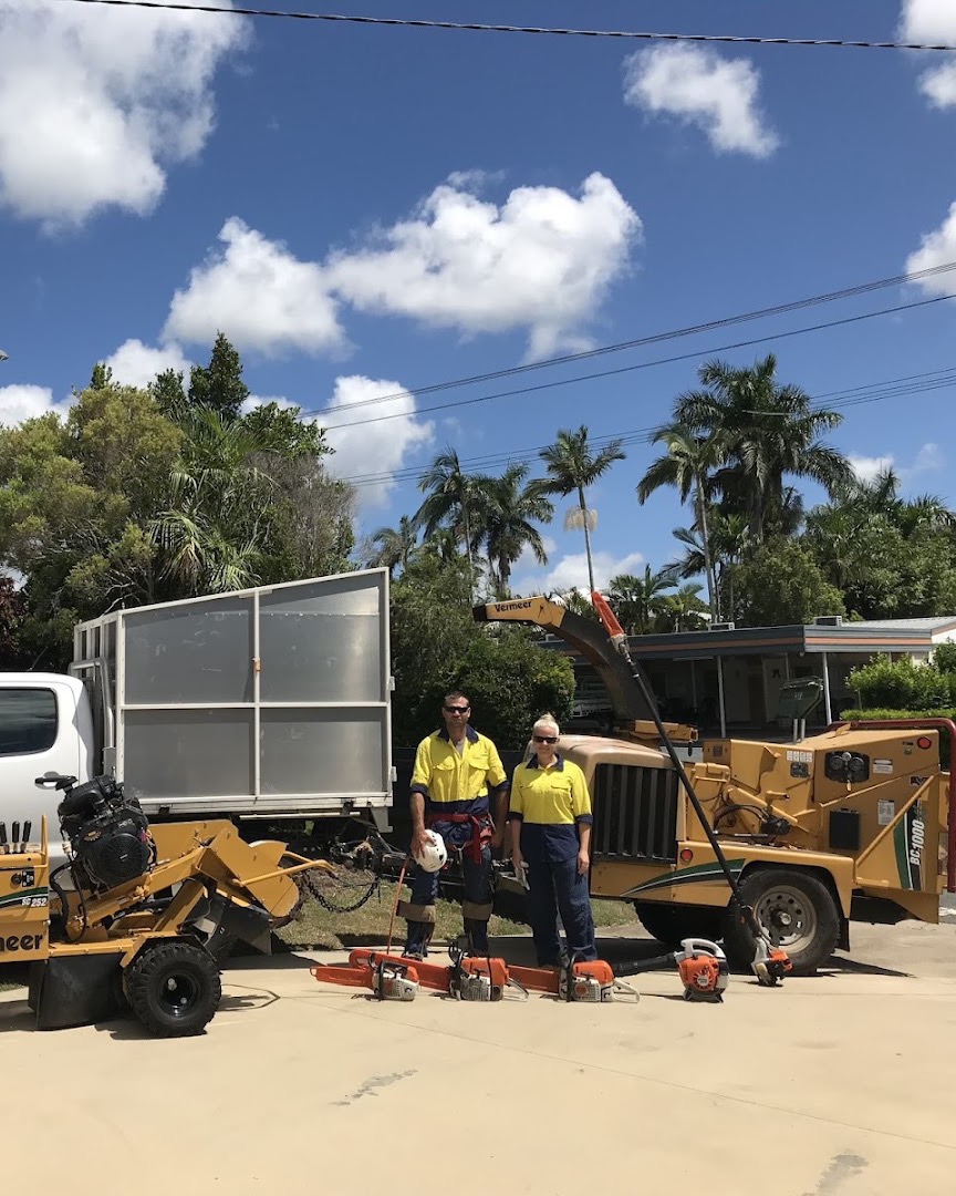 Two crew members in hi-vis standing between their tipper ute, wood chipper and stump grinder with saws lined up on the driveway